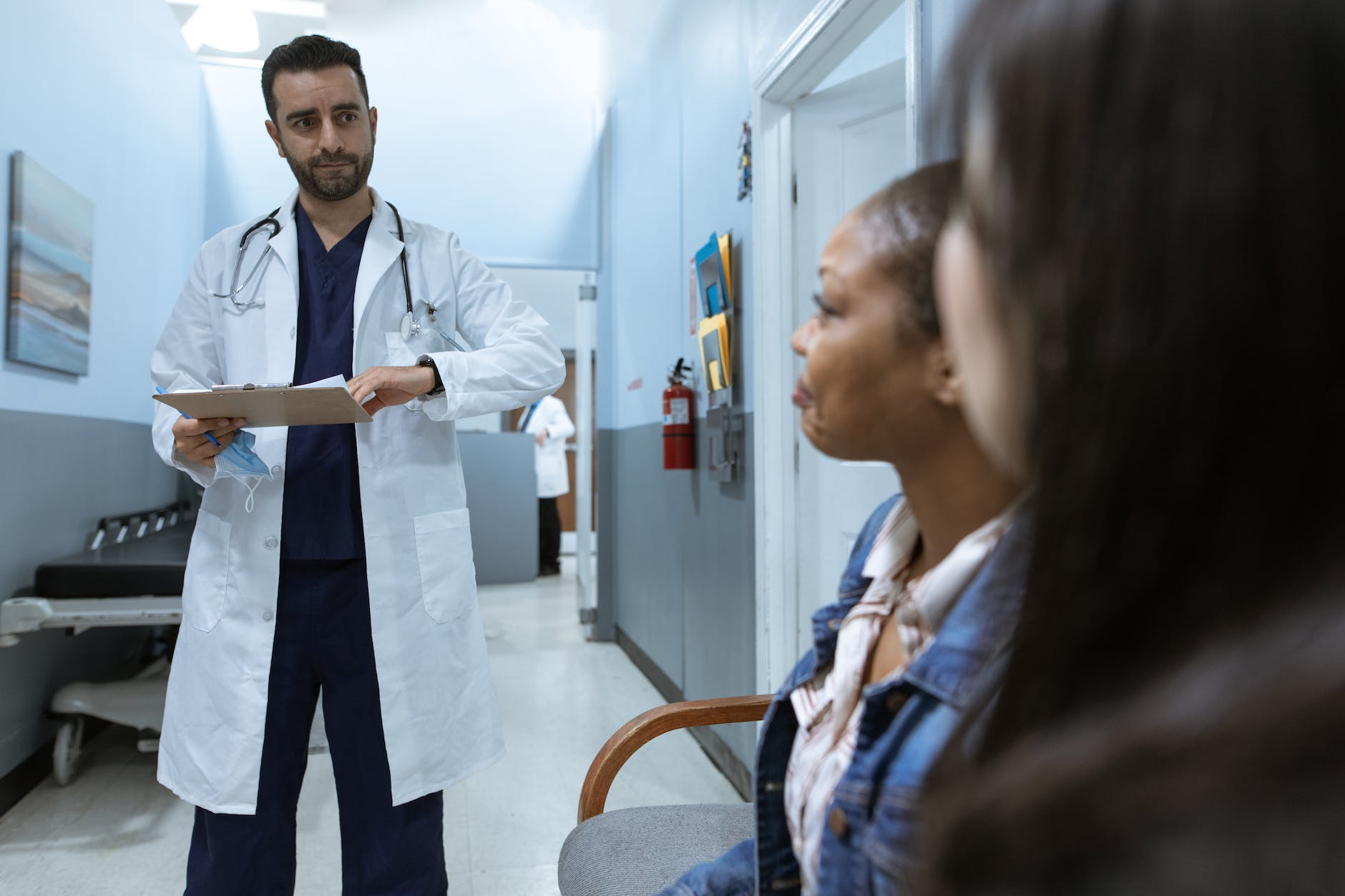 man in white medical scrub suit standing beside girl in blue denim jacket